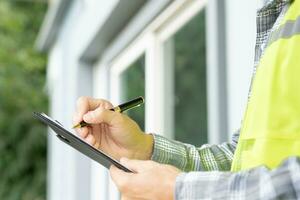 el inspector o ingeniero está inspeccionando la construcción y el aseguramiento de la calidad de la nueva casa usando una lista de verificación. ingenieros o arquitectos o contratistas trabajan para construir la casa antes de entregársela al propietario foto