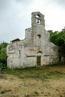 an old church with a bell tower in the middle of a field photo