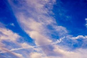 a plane flying through the sky with contrails photo