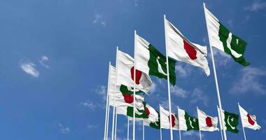 pakistan och japan flaggor vinka tillsammans i de himmel, sömlös slinga i vind, Plats på vänster sida för design eller information, 3d tolkning video