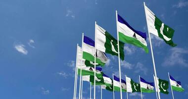 Pakistán y Lesoto banderas ondulación juntos en el cielo, sin costura lazo en viento, espacio en izquierda lado para diseño o información, 3d representación video
