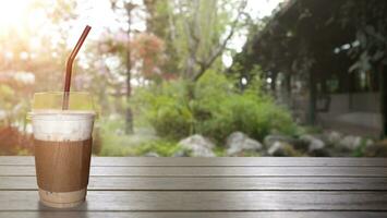 con hielo capuchino café en un claro vaso Listo a beber. en un marrón de madera mesa. Listo a actualizar foto