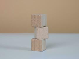 Three stacked light brown wooden cube blocks. on a white-brown background. photo