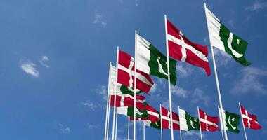 Pakistán y Dinamarca banderas ondulación juntos en el cielo, sin costura lazo en viento, espacio en izquierda lado para diseño o información, 3d representación video
