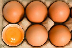 egg tray with fresh brown eggs and half-broken eggs, Fresh organic chicken eggs in carton box. photo