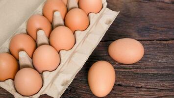 Open eggs box with fresh brown eggs on brown wooden board, Fresh organic chicken eggs in carton box. photo
