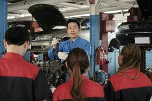 especialista conferencia, un masculino supervisor ingeniero tren y describir automotor motores con mecánico trabajador personal equipos para reparar trabajo a coche Servicio garaje y mantenimiento trabajos en automóvil industria. foto