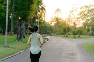 Fit Asian young woman jogging in park smiling happy running and enjoying a healthy outdoor lifestyle. Female jogger. Fitness runner girl in public park. healthy lifestyle and wellness being concept photo