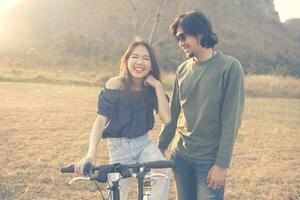 asiático mas joven hombre y mujer riendo y relajante al aire libre foto