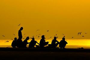 siluetas de personas pescar en un lago a puesta de sol. foto