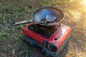 portátil gas estufa y un fritura pan en el acampar. foto