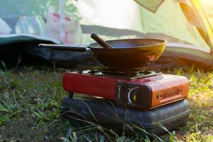 portátil gas estufa y un fritura pan en el acampar. foto