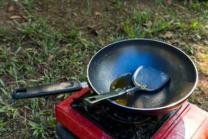 portátil gas estufa y un fritura pan en el acampar. foto