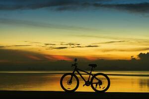 silueta de un bicicleta en un lago a crepúsculo. foto