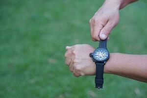 Close up man is wearing black leather hand watch, outdoor background. Concept, ashionable accessory for time telling, make you look stylish, punctual and smart. Analog wrist watch. photo