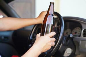 Drunk man holds beer bottle in car. Concept, Stop driving while drinking alcohol beverage or whiskey campaign. Illegal and dangerous to drive vehicle that leads to accident photo