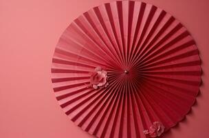 ai generado un rojo ventilador es colgado desde un rosado pared foto