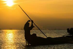 Silhouette fisherman and Sunset sky on the lake. photo