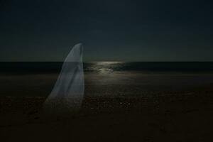 Low key image of ghost in the night on the beach. photo