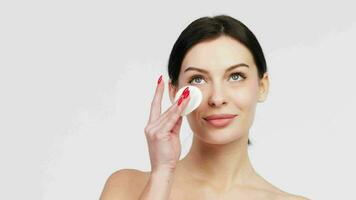 Close up beauty portrait of a young attractive woman cleaning her face with a cotton pad isolated over white background. Perfect Fresh Skin. Pure Beauty Model. Care Concept. video