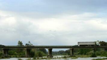 auto's en vrachtwagens circulerend Aan een brug over- een rivier- met water video