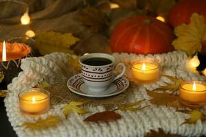cup of coffee on the autumn background with leaves and candles photo