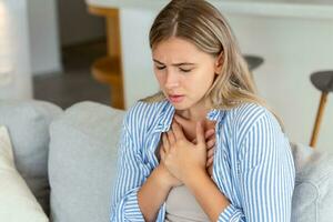 Young woman having chestpain,Acute pain, possible heart attack.Effect of stress and unhealthy lifestyle concept. photo