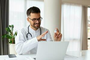 Happy young GP doctor holding distant web camera meeting, giving professional consultation to patient using computer video call app, virtual healthcare event concept. photo