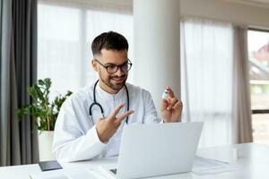 Happy young GP doctor holding distant web camera meeting, giving professional consultation to patient using computer video call app, virtual healthcare event concept. photo
