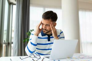 Businessman office working holding sore head pain from desk working and sitting all day using laptop computer or notebook suffering headache sick worker overworking concept photo