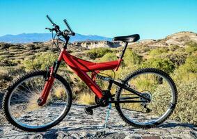 a red mountain bike sitting on top of a rock photo