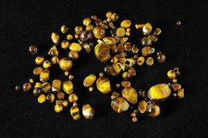 a pile of tiger eye stones on a black surface photo