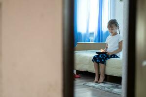 Remote lessons. The child smiles happily and gets knowledge remotely. Little girl study online learning from home with laptop. Online school. photo