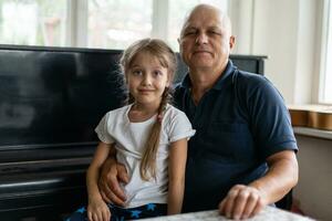 mayor abuelo con pequeño nieta adentro sentado a mesa. foto