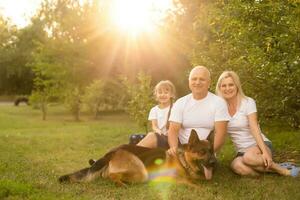 retrato de un extendido familia con su mascota perro sentado a el parque foto