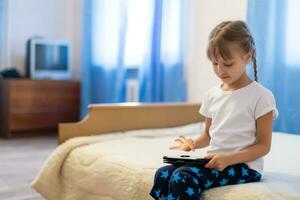 Cute young child using a digital tablet in a home interior photo