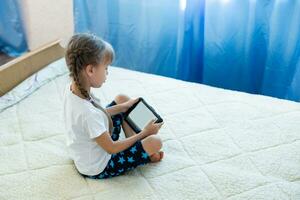 Remote lessons. The child smiles happily and gets knowledge remotely. Little girl study online learning from home with laptop. Online school. photo