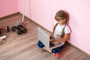 Remote lessons. The child smiles happily and gets knowledge remotely. Little girl study online learning from home with laptop. Online school. photo