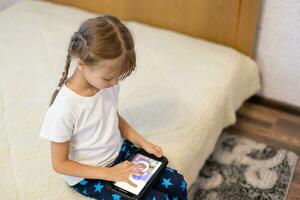 Cute young child using a digital tablet in a home interior photo