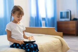 Remote lessons. The child smiles happily and gets knowledge remotely. Little girl study online learning from home with laptop. Online school. photo