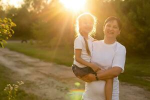 Mother and daughter having fun in the park. Happy family concept. Beauty nature scene with family outdoor lifestyle. Happy family resting together. Happiness and harmony in family life. photo