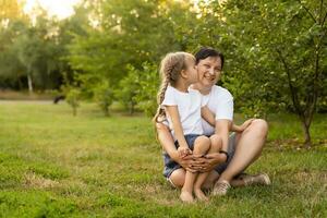 Mother and daughter having fun in the park. Happy family concept. Beauty nature scene with family outdoor lifestyle. Happy family resting together. Happiness and harmony in family life. photo