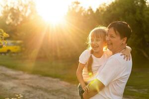 Mother and daughter having fun in the park. Happy family concept. Beauty nature scene with family outdoor lifestyle. Happy family resting together. Happiness and harmony in family life. photo