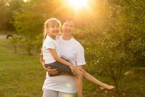 Mother and daughter having fun in the park. Happy family concept. Beauty nature scene with family outdoor lifestyle. Happy family resting together. Happiness and harmony in family life. photo