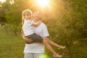 Mother and daughter having fun in the park. Happy family concept. Beauty nature scene with family outdoor lifestyle. Happy family resting together. Happiness and harmony in family life. photo