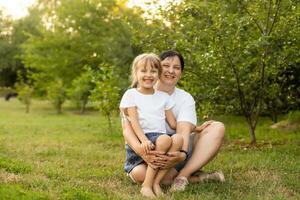 Mother and daughter having fun in the park. Happy family concept. Beauty nature scene with family outdoor lifestyle. Happy family resting together. Happiness and harmony in family life. photo