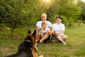 retrato de un extendido familia con su mascota perro sentado a el parque foto