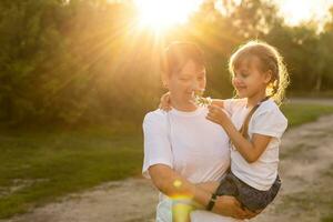 Mother and daughter having fun in the park. Happy family concept. Beauty nature scene with family outdoor lifestyle. Happy family resting together. Happiness and harmony in family life. photo