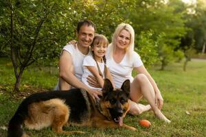 retrato de un extendido familia con su mascota perro sentado a el parque foto
