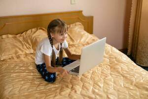 education, free time, technology and internet concept - little student girl with laptop pc at home photo